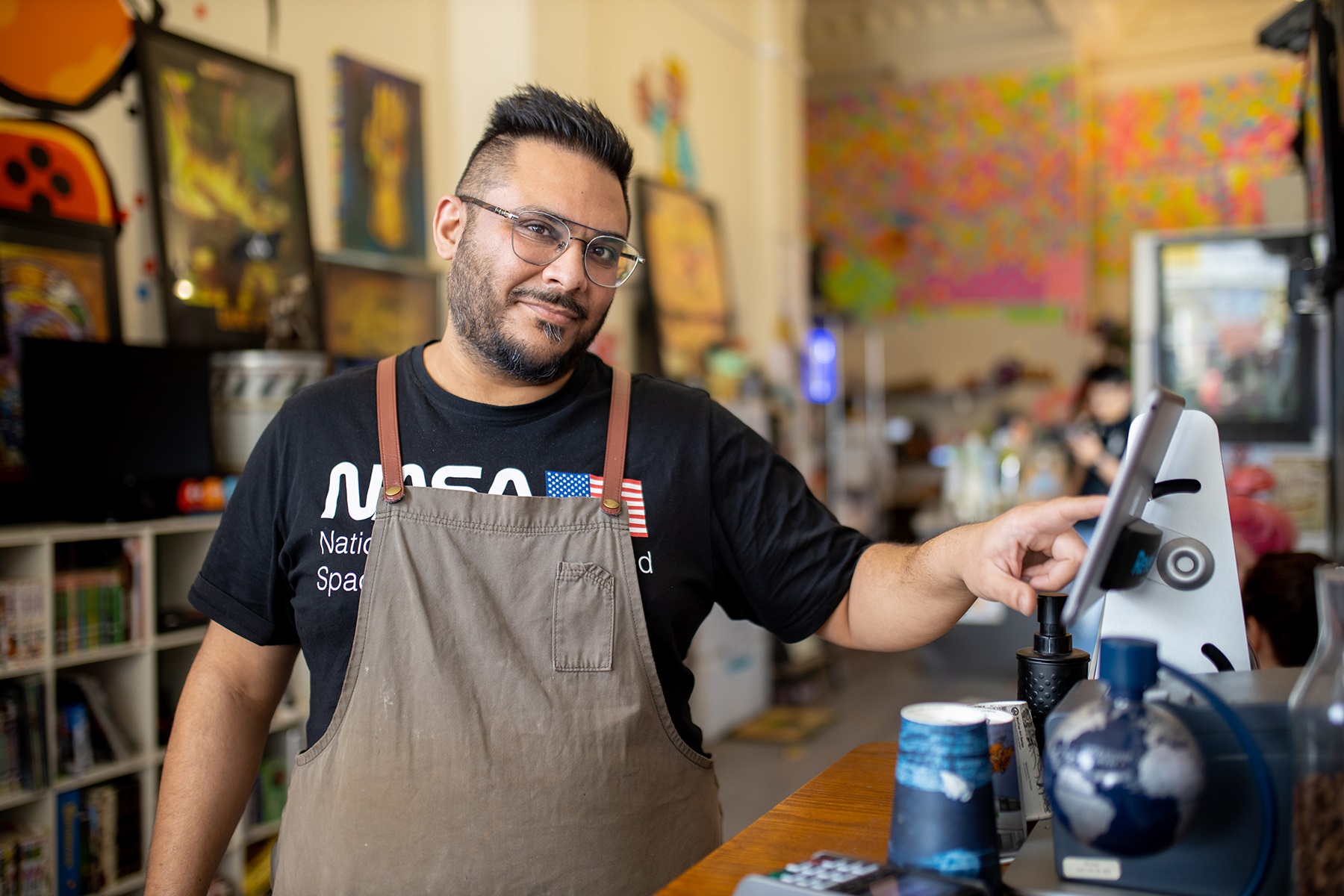 Photo of Dharmesh Patel, owner of Game City Espresso, putting through an order in his coffee shop. 